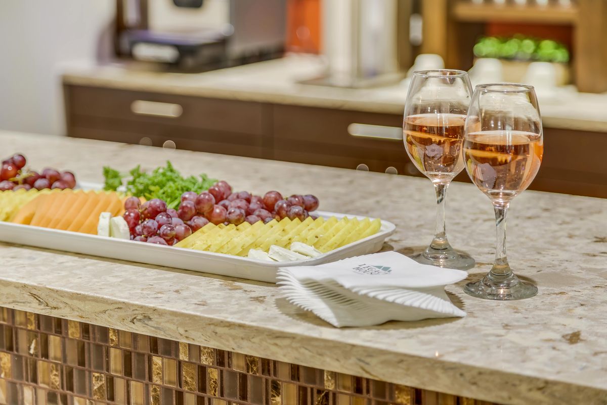 A countertop set with a cheese platter accompanied by grapes and two glasses of wine, ready for serving.