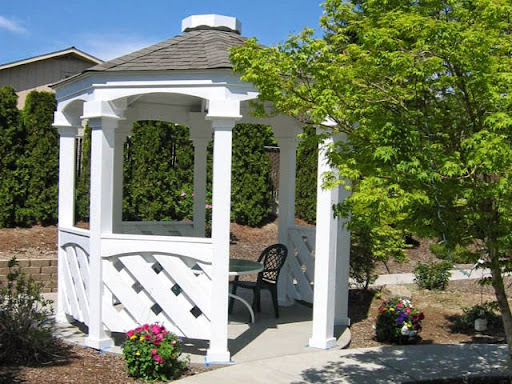 A charming white gazebo nestled in a beautiful garden, perfect for relaxation.