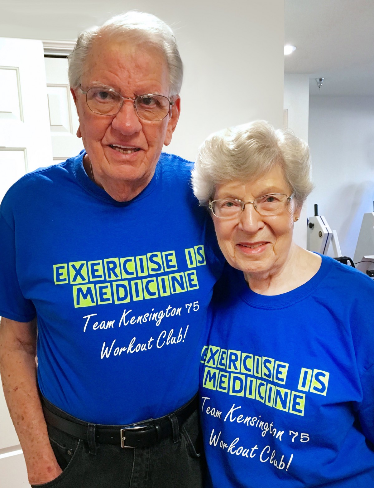 An elderly couple wearing matching blue t-shirts promoting exercise as medicine.