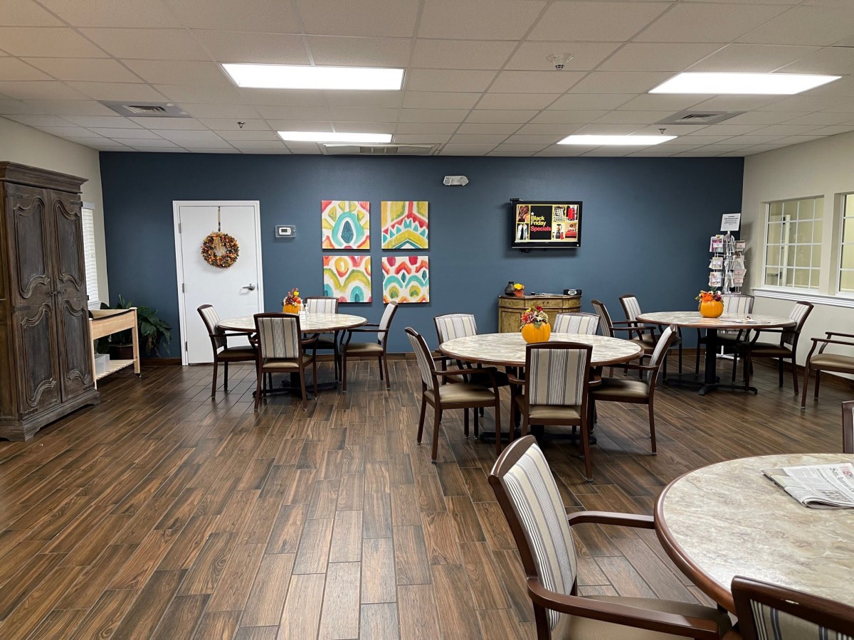A cozy dining area with round tables and chairs, decorated with colorful artwork on the walls.