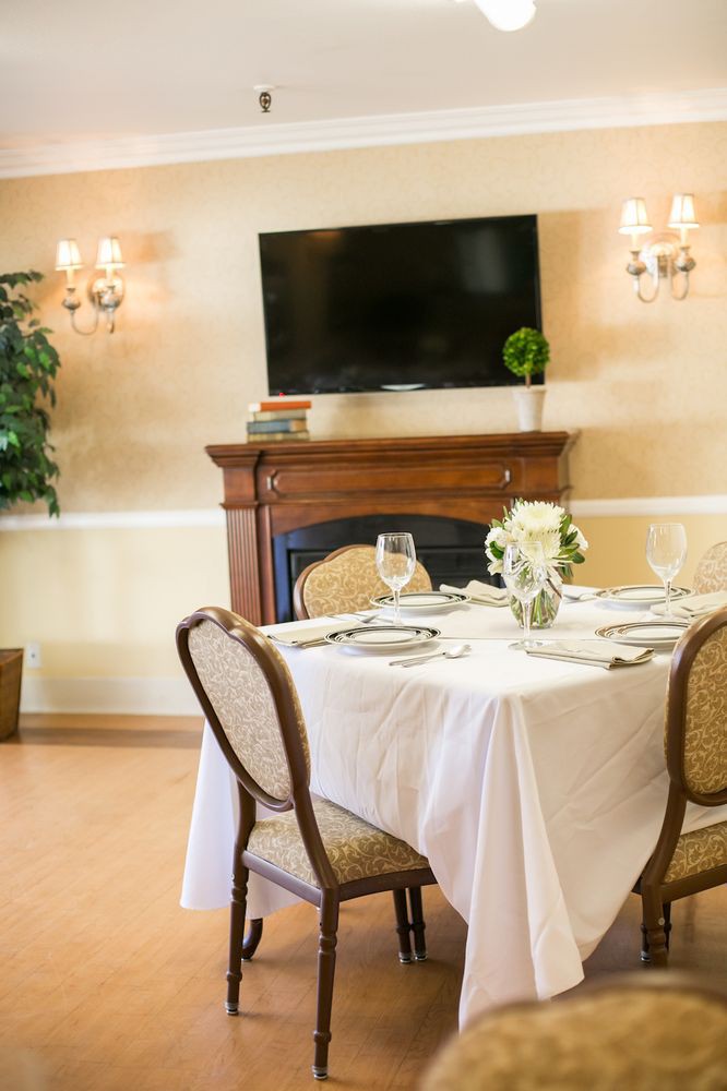 An elegantly set dining table in a well-decorated room with a fireplace and television.