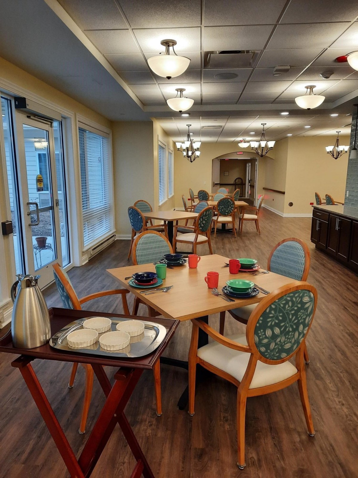 A neatly arranged dining room with tables set for a meal, featuring elegant chairs and soft lighting.