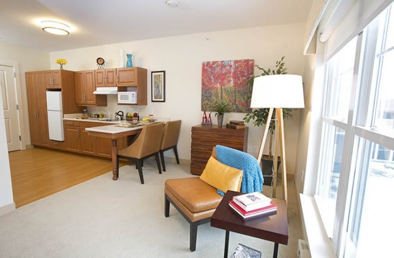 A cozy apartment interior featuring a living room and kitchen with warm-toned furniture and decor.