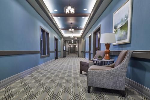 A stylish hotel hallway with patterned carpet, seating area, and elegant lighting.