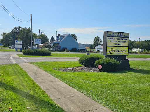 A business sign stands by the roadside, surrounded by neatly trimmed grass and landscaping.