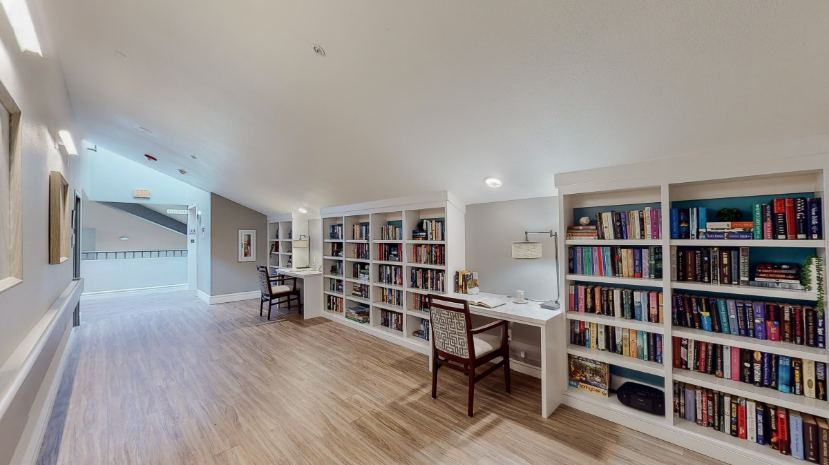 A spacious home office with built-in bookshelves, a desk, and wood flooring.