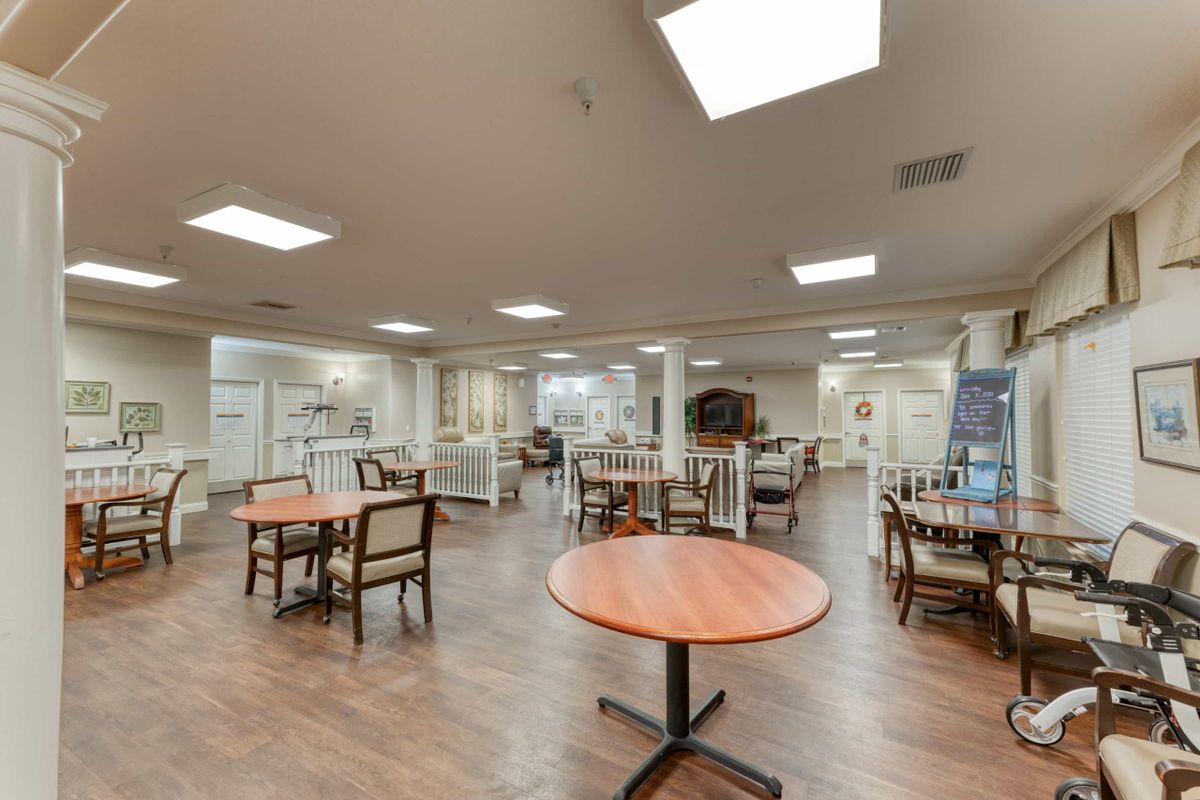 A spacious dining area featuring tables and chairs, illuminated by overhead lights.