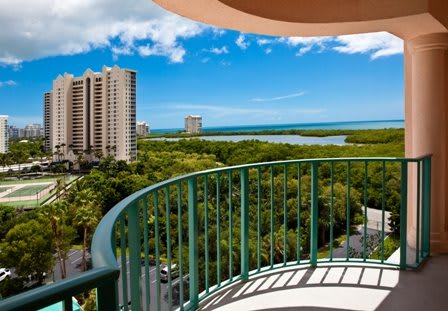 A scenic view from a balcony overlooking the cityscape, with lush greenery and bodies of water under a clear blue sky.