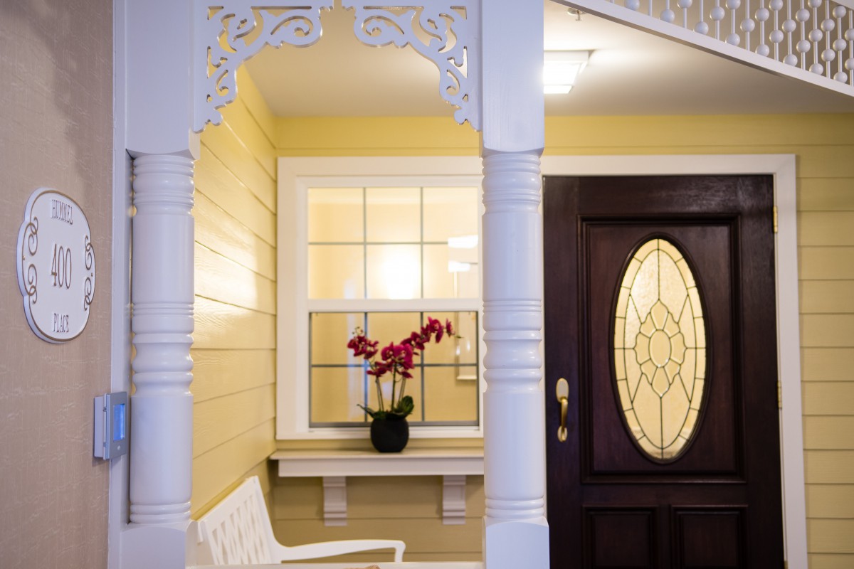 A welcoming porch with a decorative door, large window, and a flower pot on display.