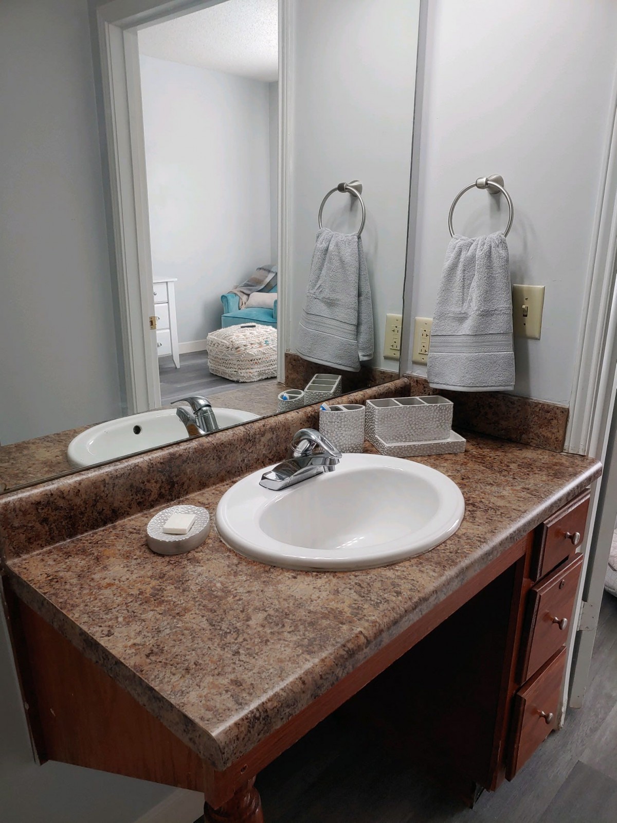 A clean bathroom sink with a mirror and hanging towels.
