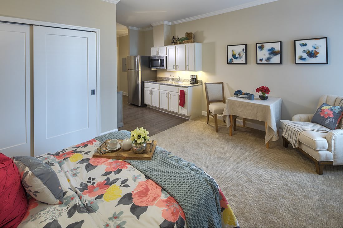 A cozy studio apartment with a bed, kitchenette, and a small dining area.