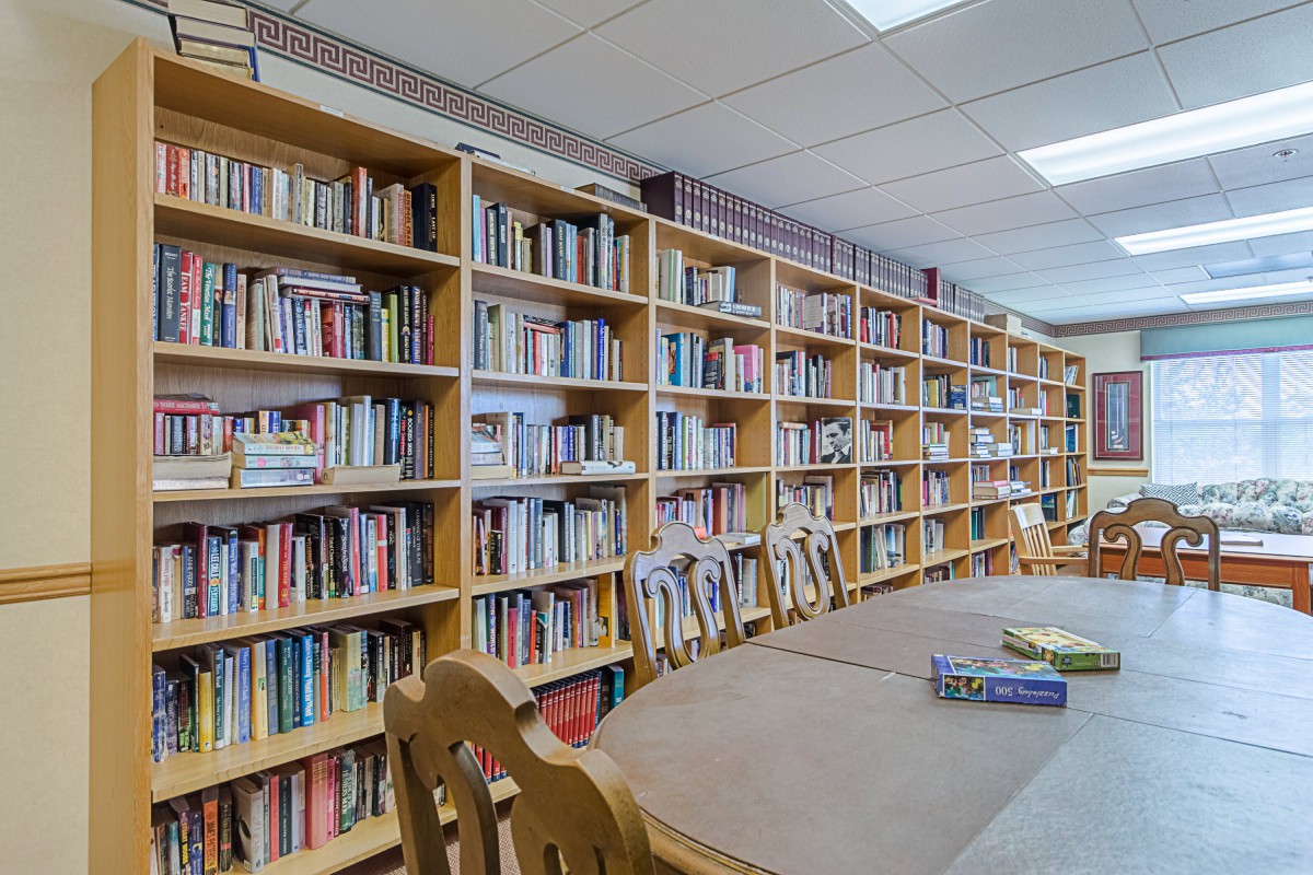 A quiet library room with rows of bookshelves and a reading table.