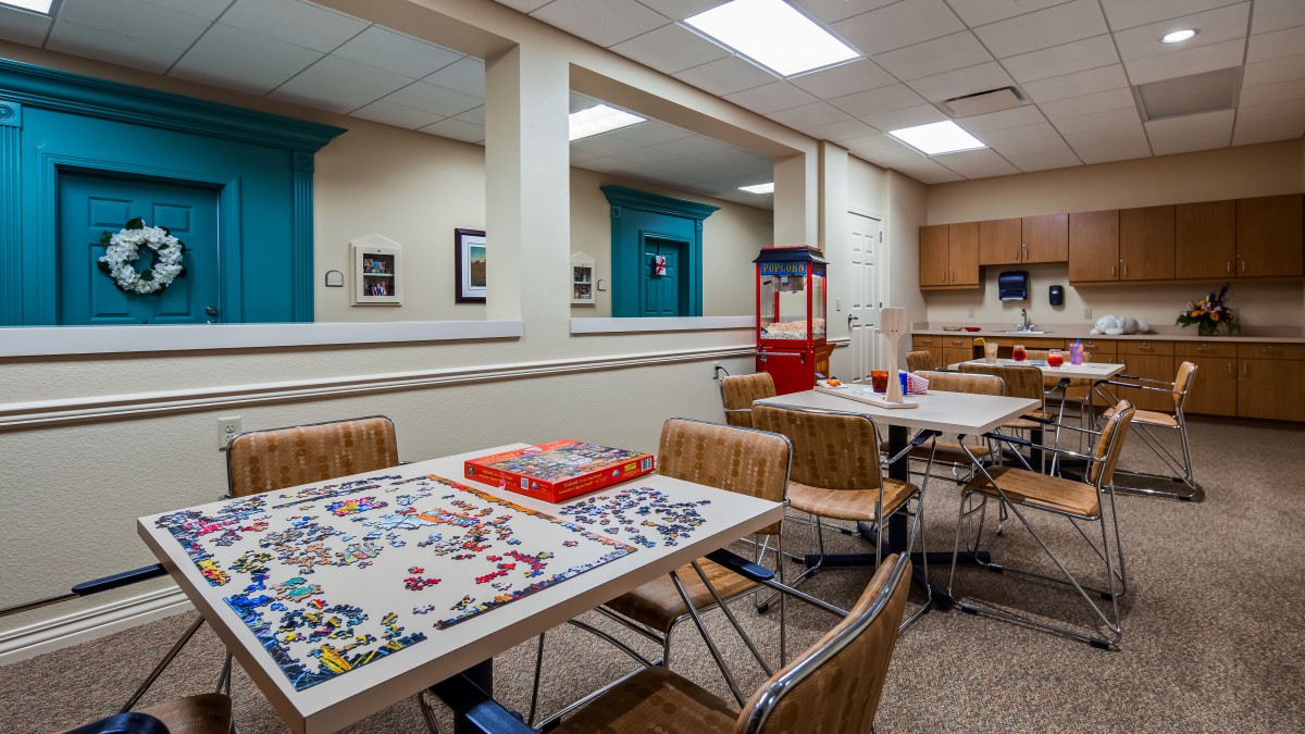A cozy game room with puzzles on the tables and a popcorn machine in the corner.