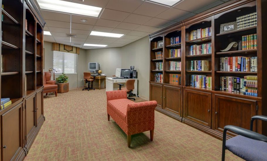 A cozy library with bookshelves, computers, and seating area.