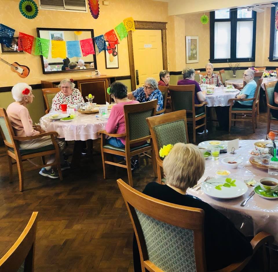 A group of elderly people enjoying a meal together in a decorated dining room.