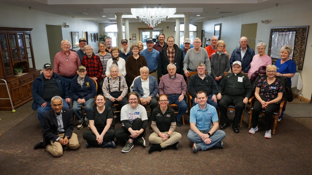 A group of elderly individuals posing for a community photo indoors.