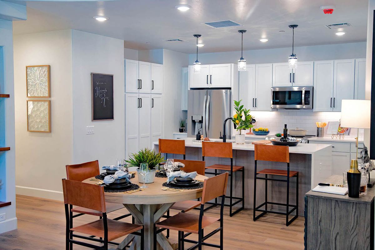 A modern kitchen and dining area featuring a sleek design with bar stools and a well-set table.