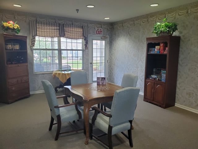 Cozy dining area with a wooden table and chairs, surrounded by windows letting in natural light.