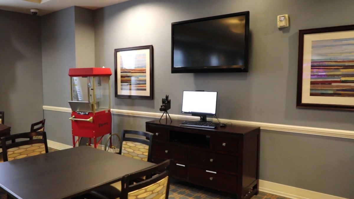 A conference room featuring a television, computer on a desk, and a popcorn machine.