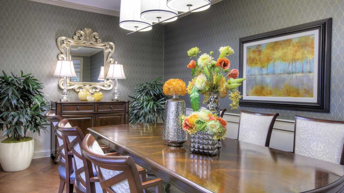 A beautifully decorated dining room featuring a wooden table with floral centerpieces, elegant chairs, and stylish wall decor.