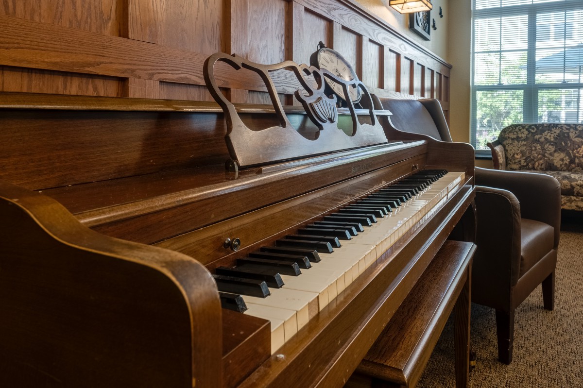 A classic wooden piano with a row of gleaming keys in a warmly lit room.