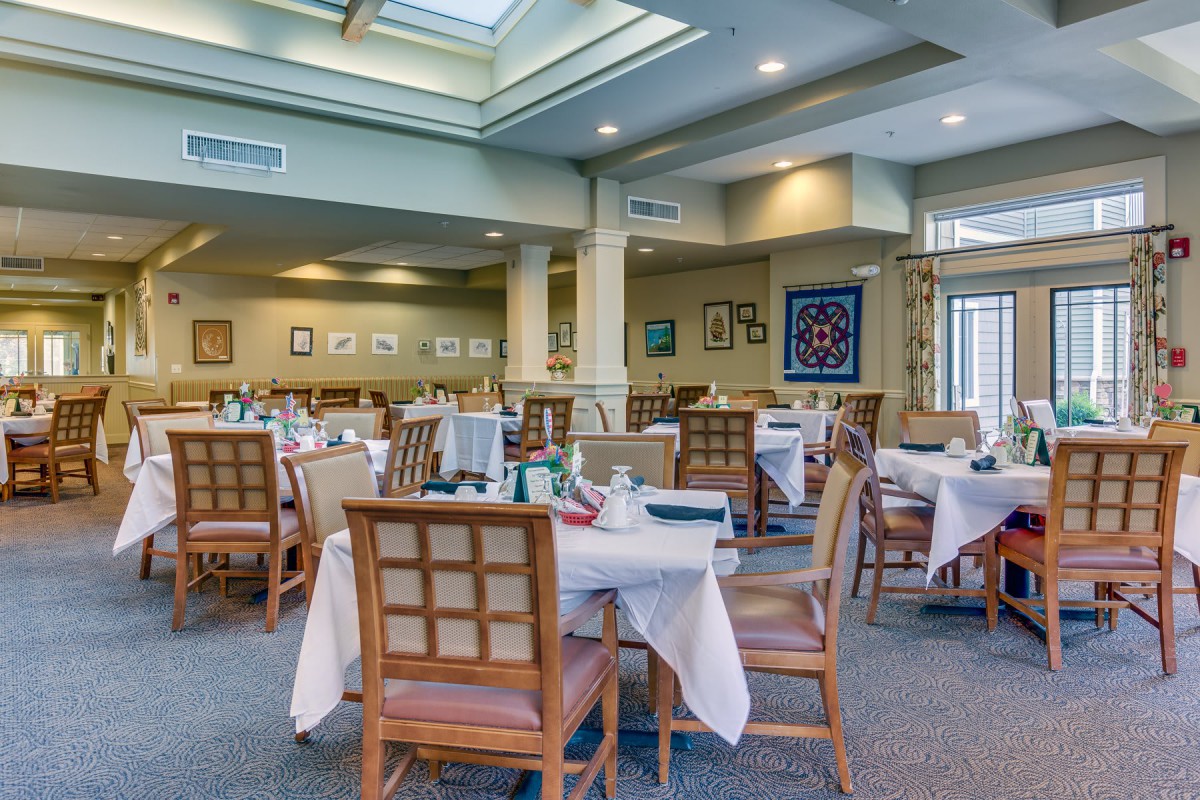 An elegant dining area with tables set for guests, featuring a skylight and tasteful decor.