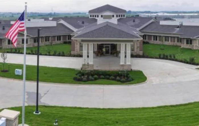 A large building with a central entrance and surrounding green lawn.