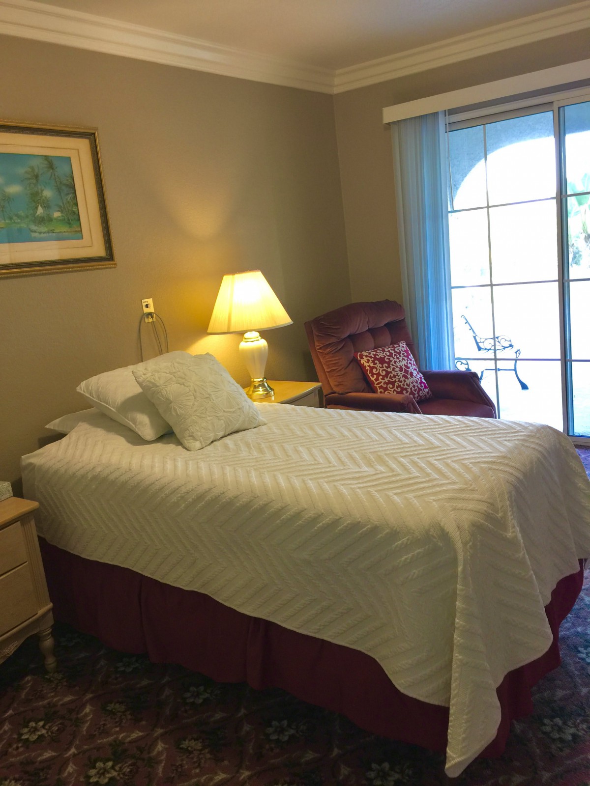 A cozy bedroom with a single bed, armchair, and a window.