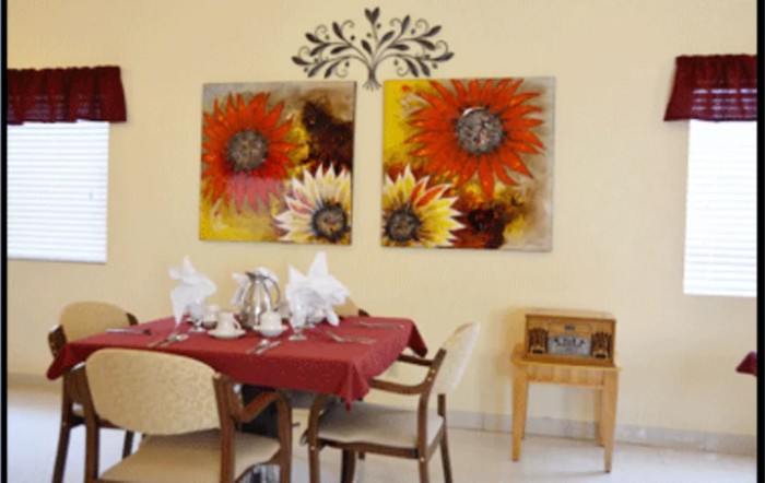 A cozy dining area featuring vibrant floral wall art, a red tablecloth, and elegant table settings.