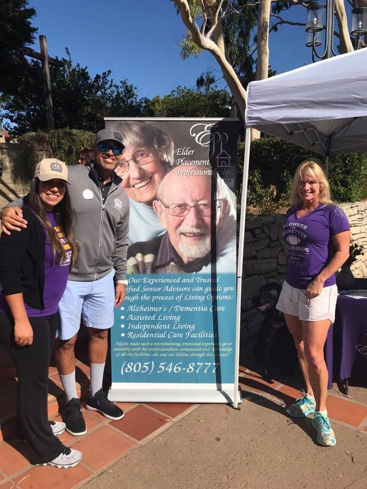 Group of people posing beside a promotional banner at an outdoor event.