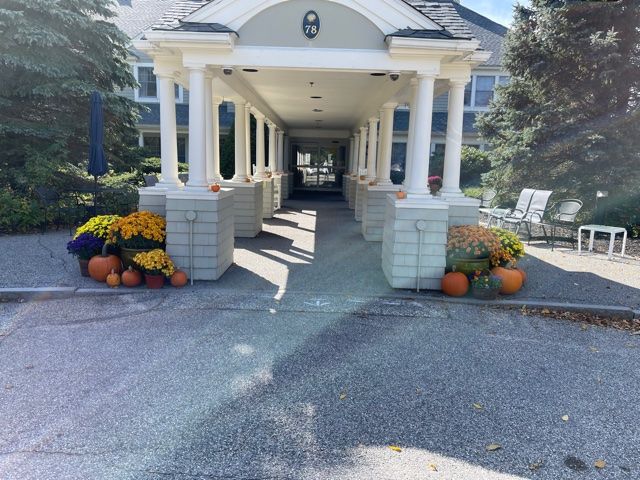 A covered entrance with columns decorated with pumpkins and flowers.