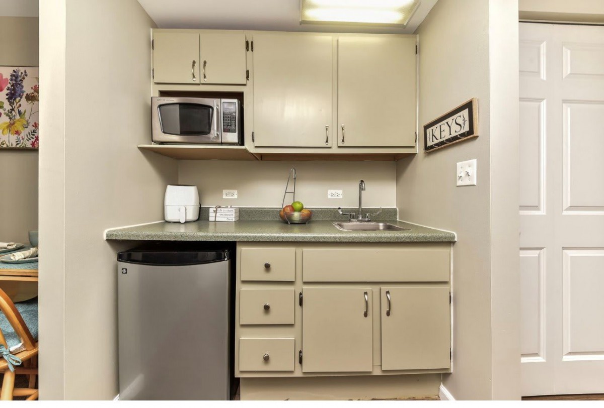 A compact kitchenette with a microwave, sink, and cabinets.