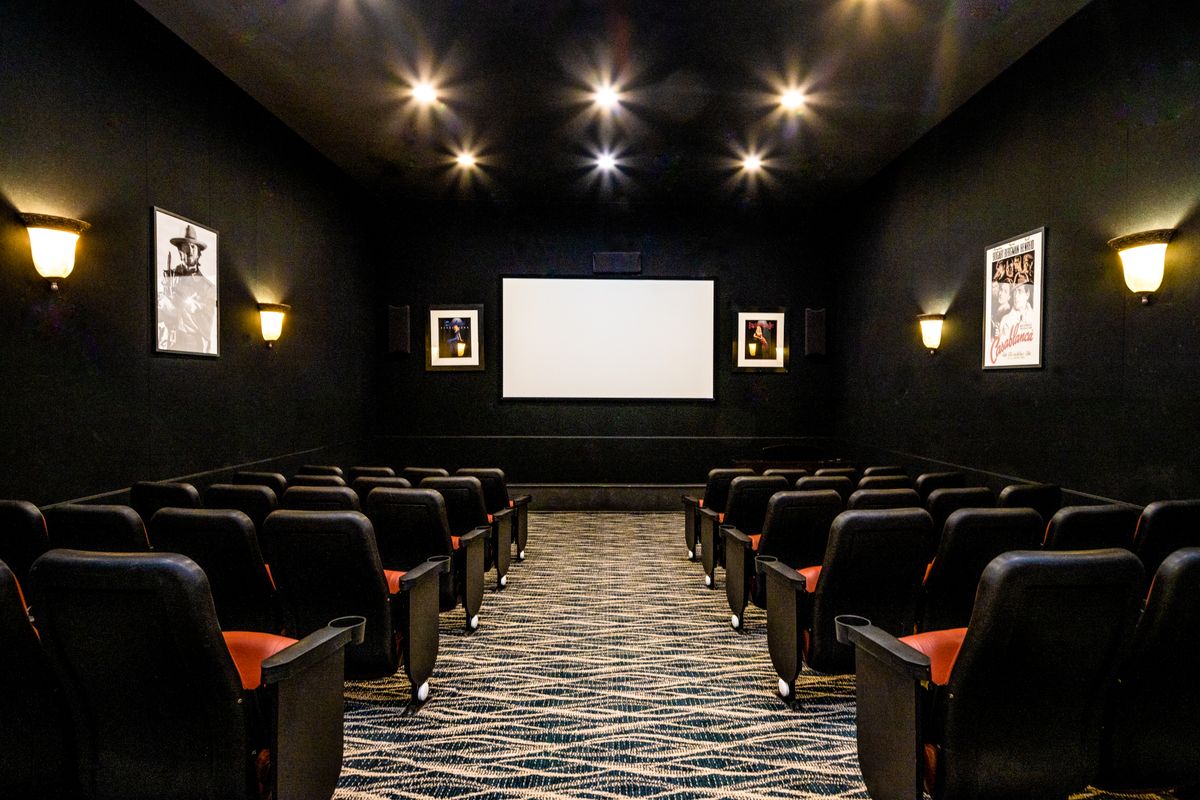 An empty movie theater with rows of seats facing a large screen.