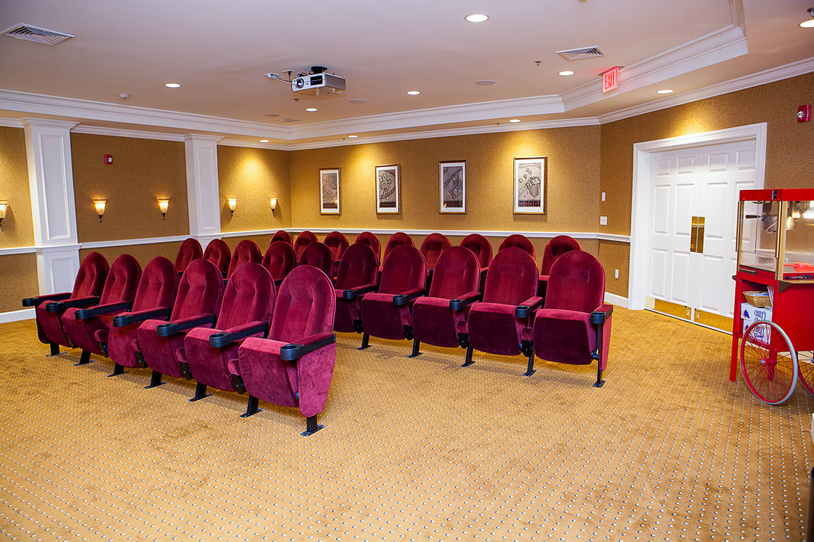 A cozy indoor theater with plush red seating and a projector setup.