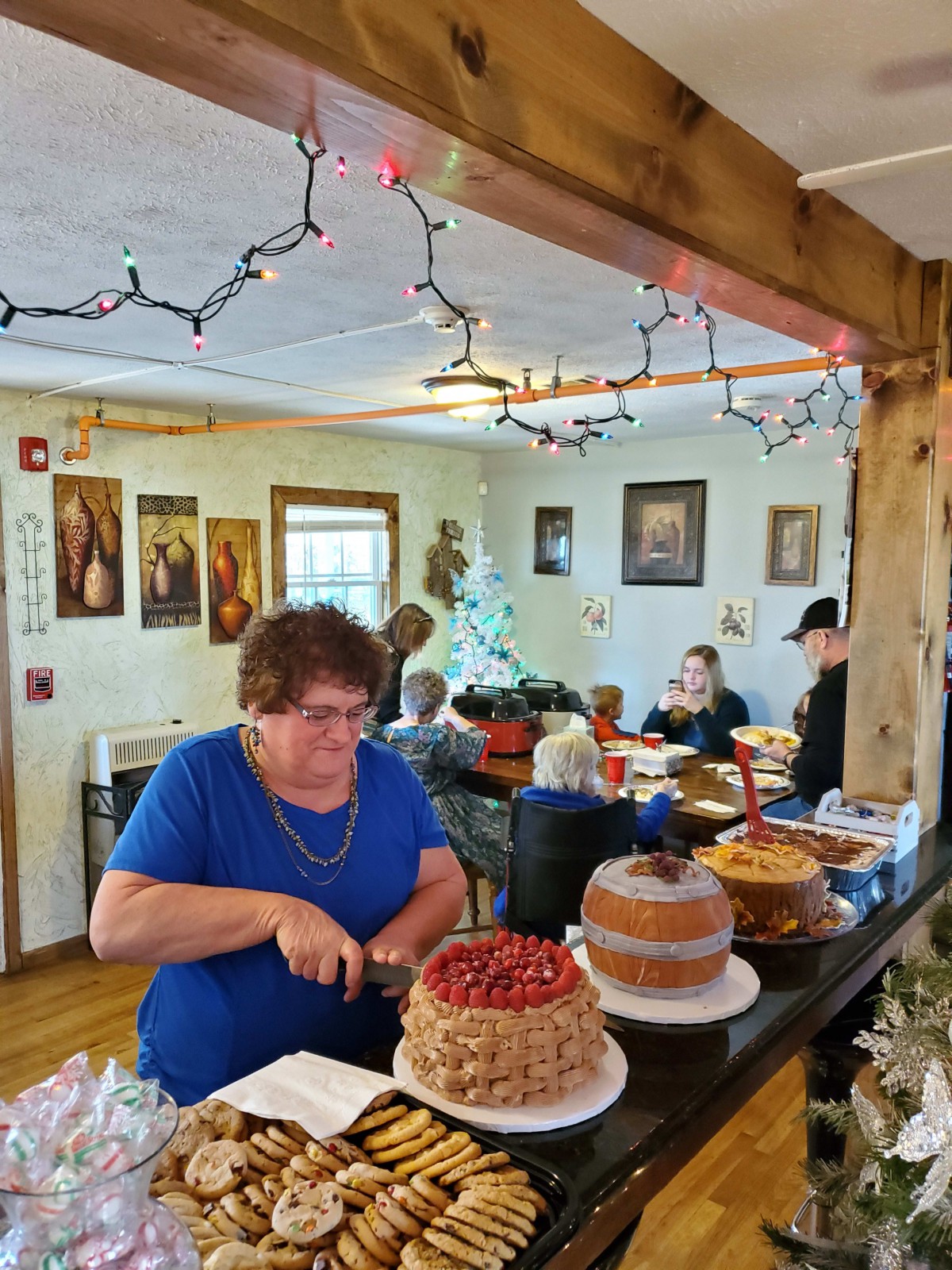 A woman cutting a cake at a family gathering with decorations in the background.
