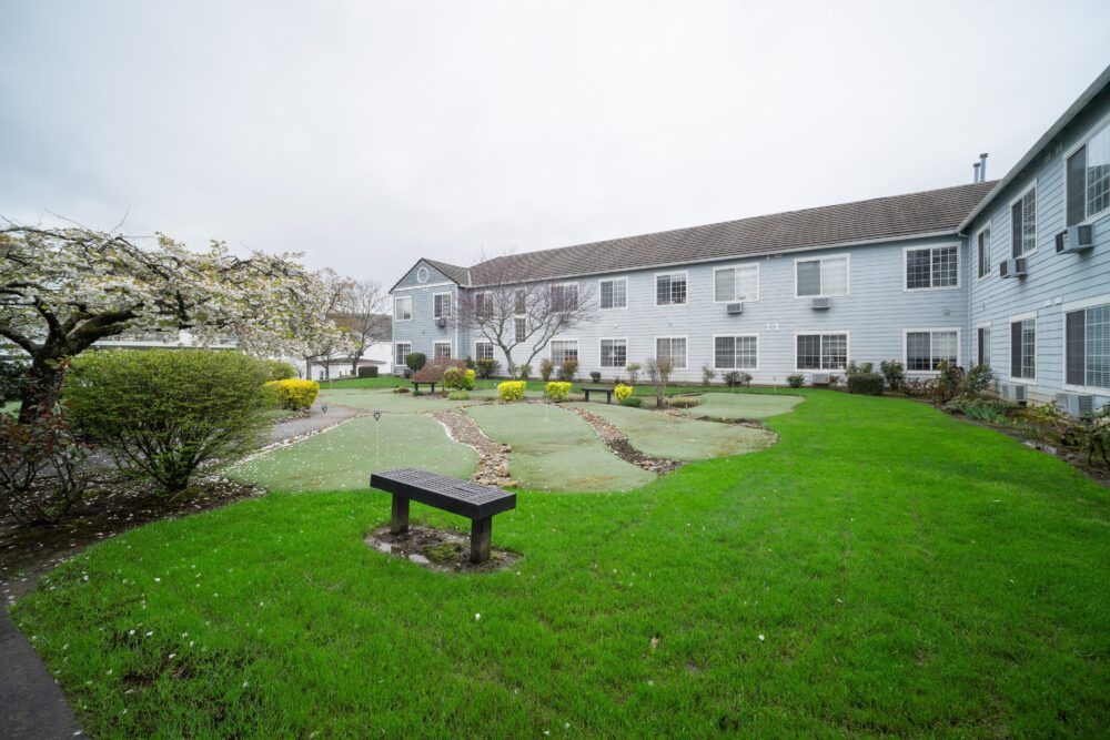 A well-maintained garden with a bench in front of a residential building on an overcast day.