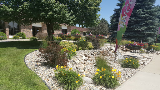 A beautifully landscaped garden featuring vibrant flowers and natural stone formations, surrounded by lush greenery on a sunny day.