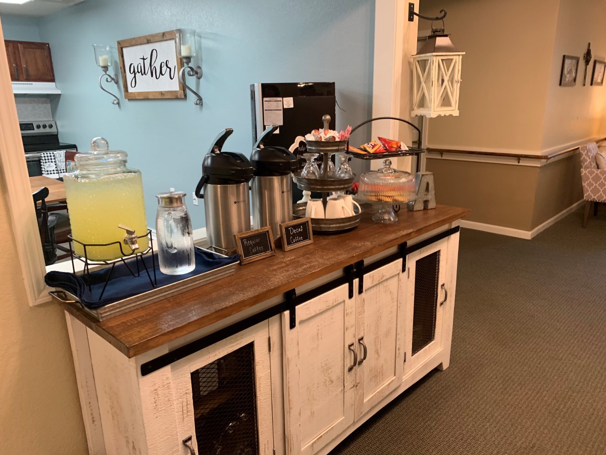 A cozy beverage station with coffee, lemonade, and snacks in a rustic setting.