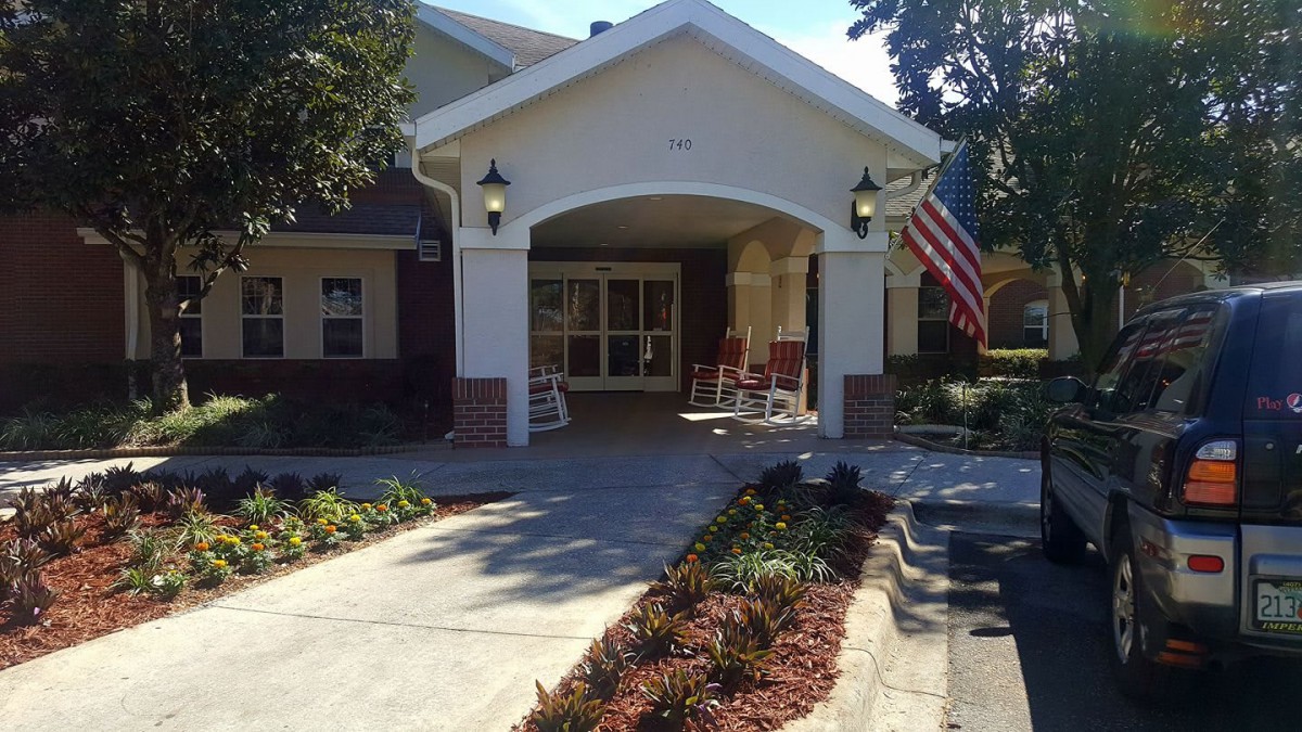 A welcoming building entrance with a garden path and American flag.