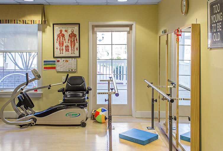 A well-lit physical therapy room equipped with exercise machines and training tools.