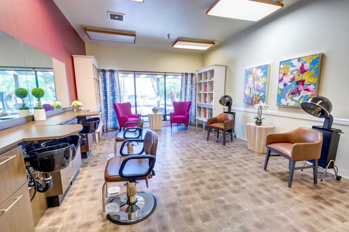 A modern salon interior with hair styling stations and large windows allowing natural light.