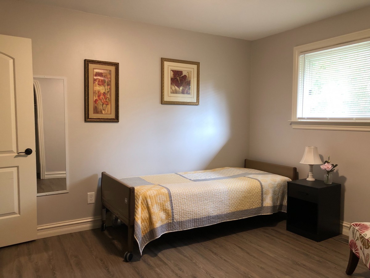 A minimalist bedroom with a single bed, nightstand, and decorative artwork on the wall.