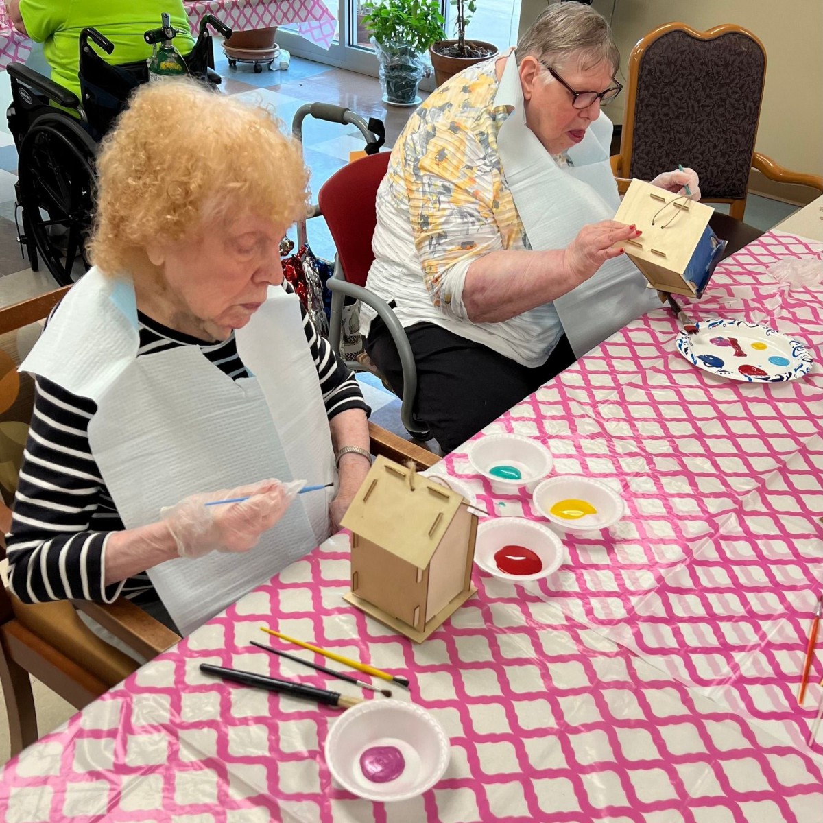 Elderly individuals engaging in a painting activity as part of an arts and crafts session.