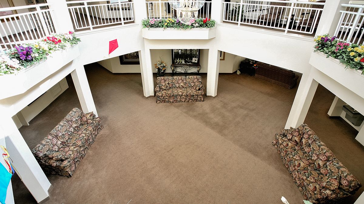 An interior view of a spacious lobby with a carpeted floor, decorative brick staircases, and balcony railings above.