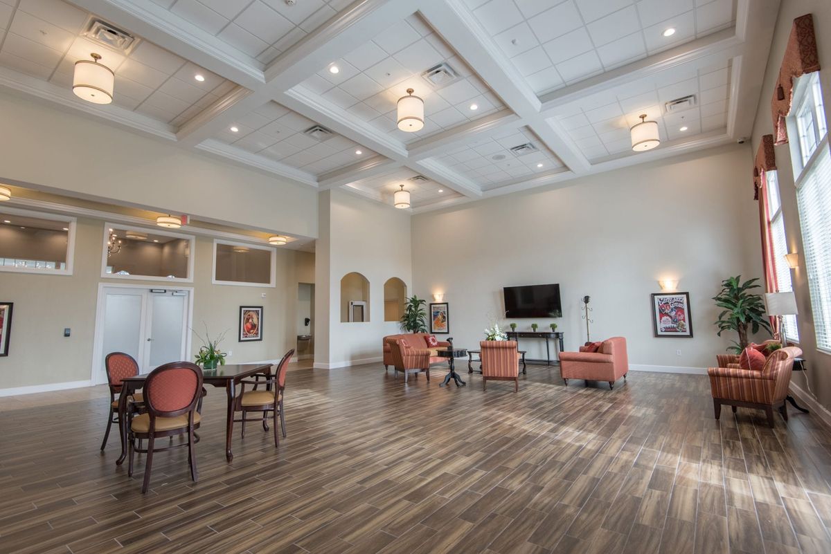 A spacious and modern lounge with elegant furniture and ceiling lights, featuring wood flooring and a television.