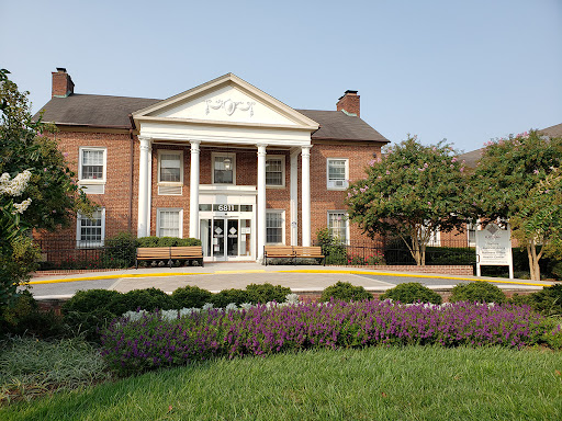 A charming brick building with a classic architectural design, surrounded by well-maintained landscaping and vibrant flowers.