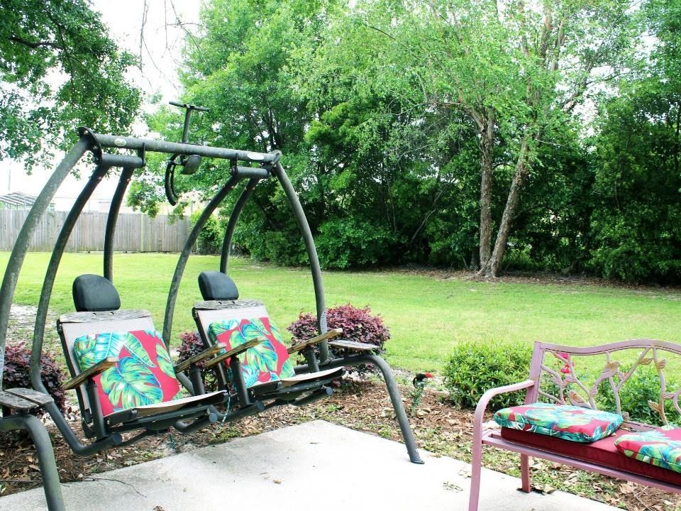 A peaceful backyard with a swing and chairs, surrounded by greenery.
