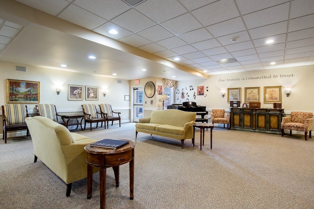 A spacious and elegantly decorated living room with comfortable seating, a piano, and artwork on the walls.