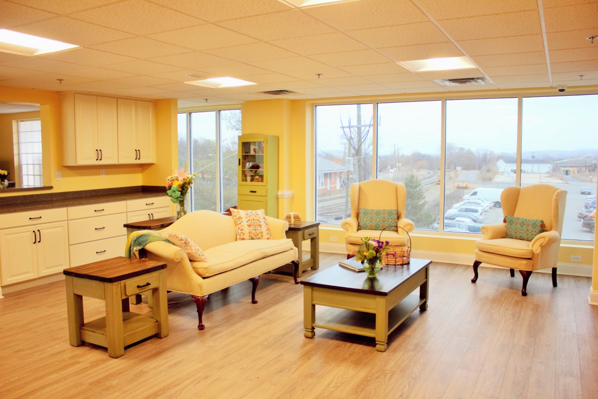 A cozy, well-lit living room featuring comfortable seating and large windows.