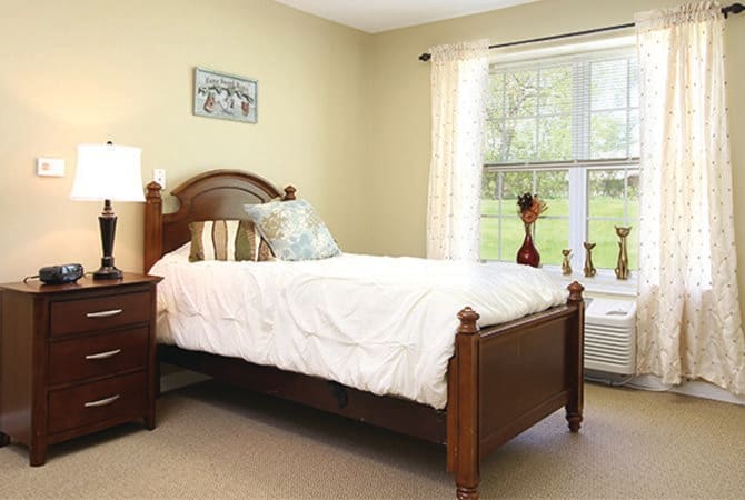A cozy bedroom with a wooden bed and a large window.